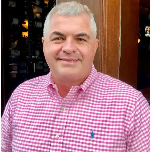 A man in a red shirt is smiling for the camera.