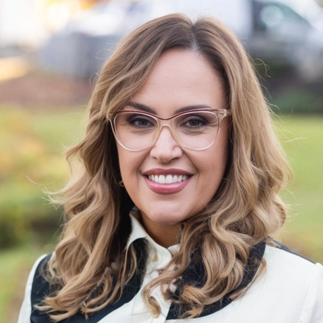 A woman with glasses and long hair wearing a white shirt.