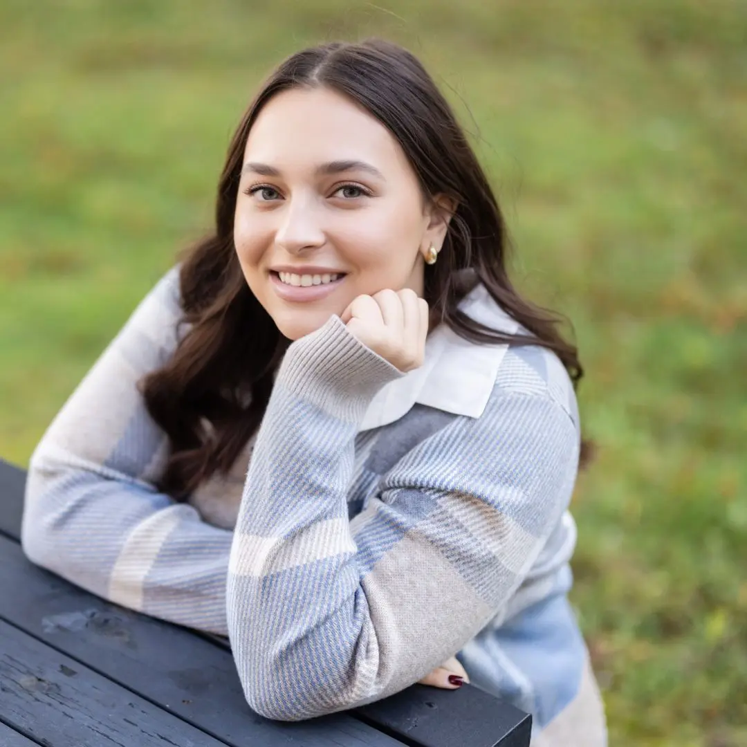 A woman sitting on top of a wooden bench.